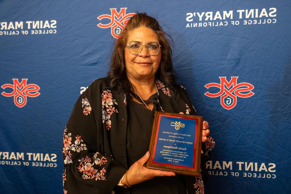 Karla Henriquez holds up a plaque for 2024 Student Leadership Awards